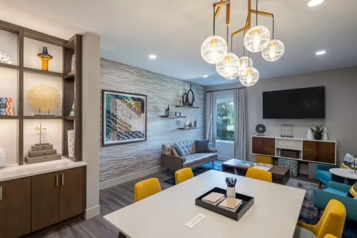 Guest lounge and meeting space with globe pendants, yellow chairs and display shelving