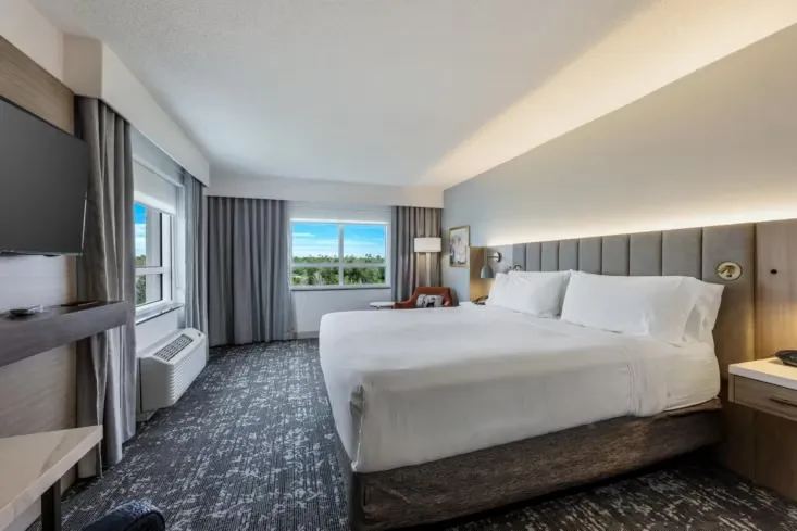 King guest room with upholstered headboard wall and water views