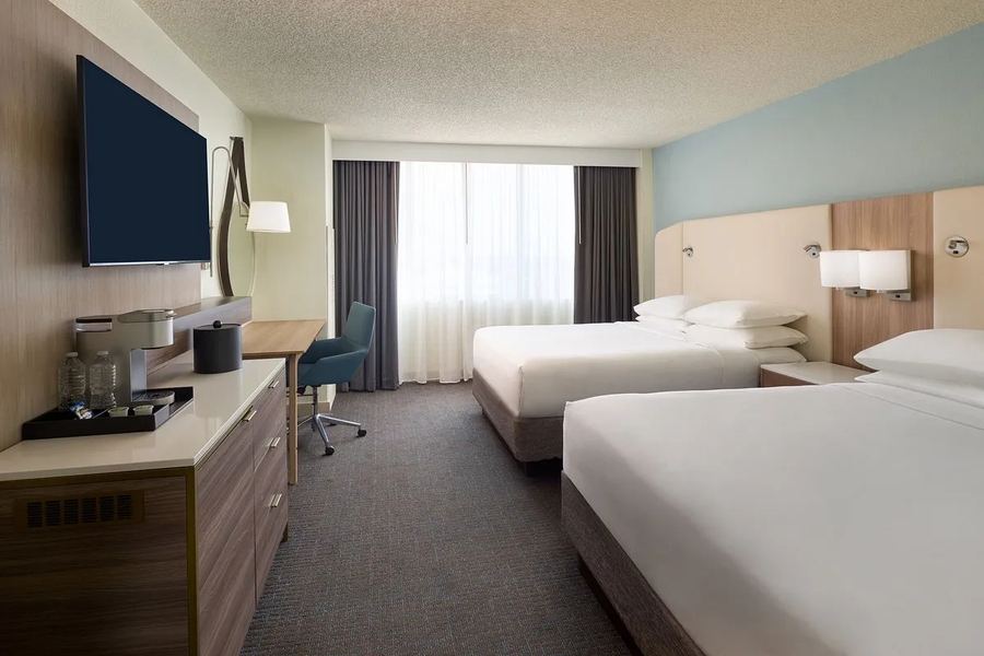 Double queen guest room with wood headboards and work desk