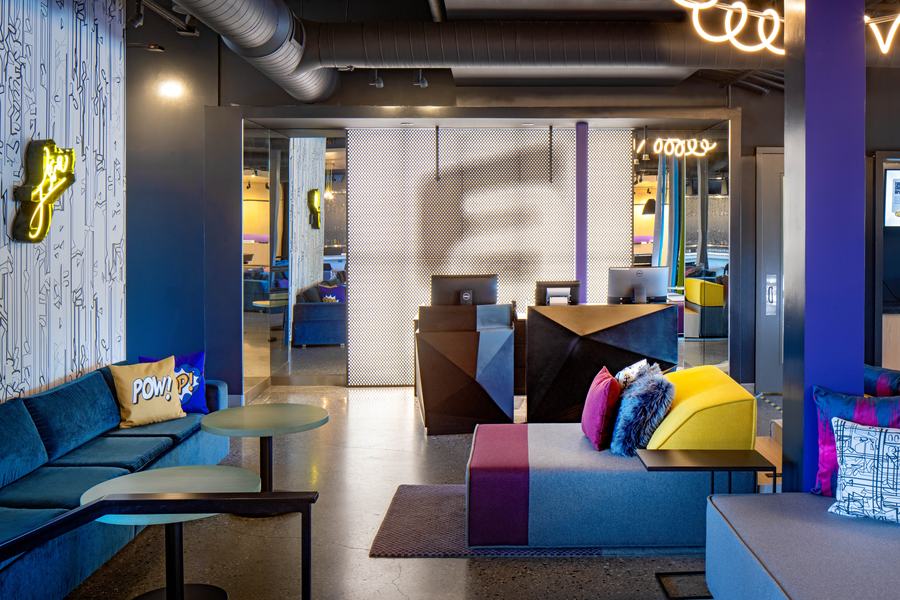 Front desk and lobby with neon accents and blue lounge seating