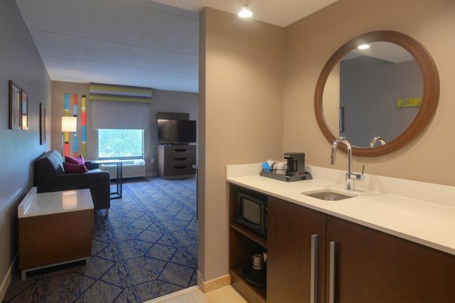 Suite entryway with wet bar and round mirror